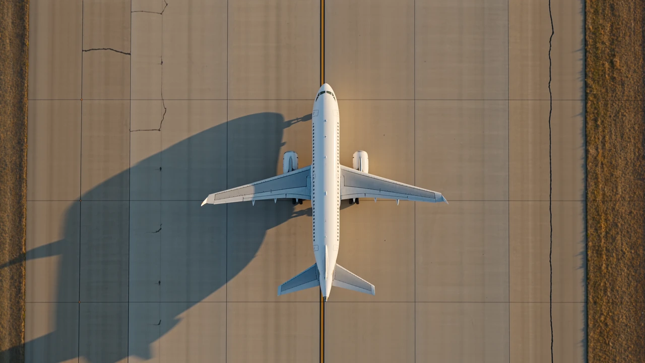 Illustrative overhead view of an aircraft moving along a taxiway in warm sunlight.